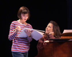 Small Alison (Lila Gold) shares a school project with her mother Helen (Crissy Guerrero) in “Fun Home,” presented by TheatreWorks Silicon Valley October 1-28 at the Mountain View Center for the Performing Arts.
NOTE: Lila appears in performances on October 3, 5, 6, 7 (7pm), 9, 11, 12, 13 (8pm), 14 (2pm), 17, 19, 20 (8pm), 21 (2pm), 24 (7:30pm), 25 (2pm), 26, 27.
